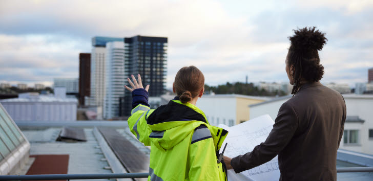 På bilden visas två byggnadsarbetare på en byggarbetsplats.