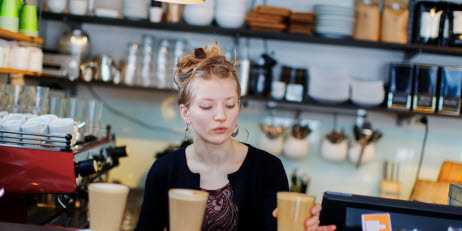 Ung tjej som serverar kaffe på ett café