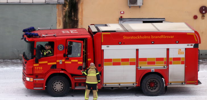 En röd brandbil utanför en brandstation.