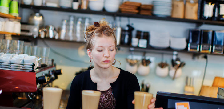 Ung tjej som serverar kaffe på ett café